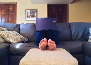 An image showing person sitting on the couch browsing on his laptop